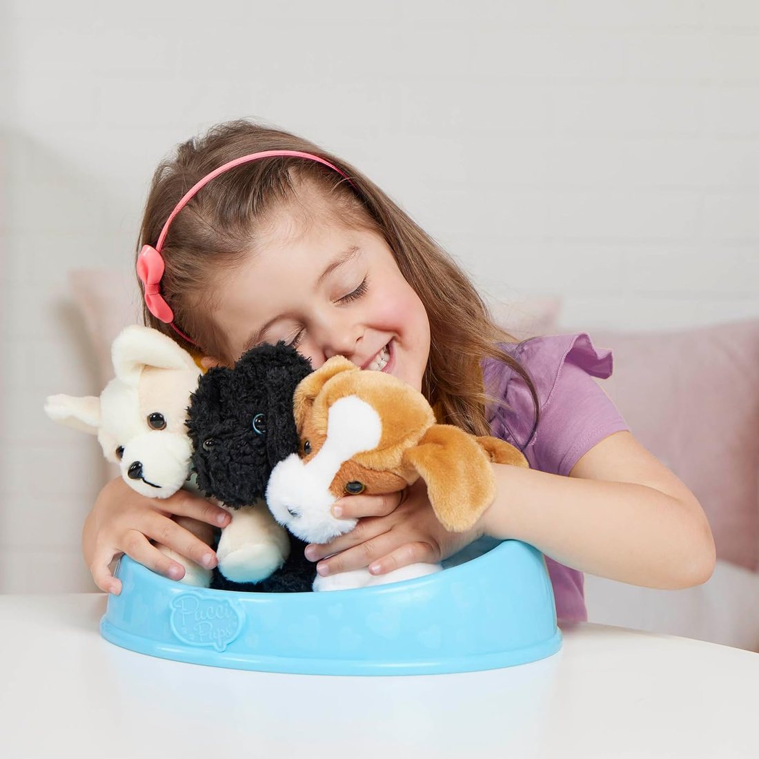 A girl hugging three Pucci Pups adopt-a-pup puppies in their bed